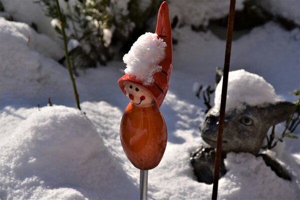 Eine lächelnde Gartendekoration mit Schnee auf der Mütze.